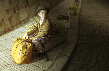 Child on a road with vintage bag. Vintage clothes styleの写真素材