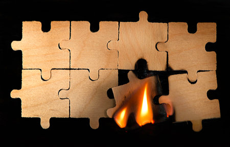 Burning wooden puzzle on dark background. Close up