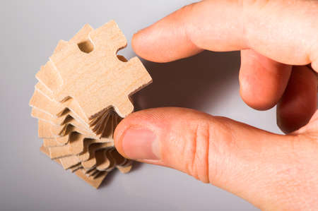 Wooden puzzle on white background. Pile of puzzle. Hand holding puzzle piece.