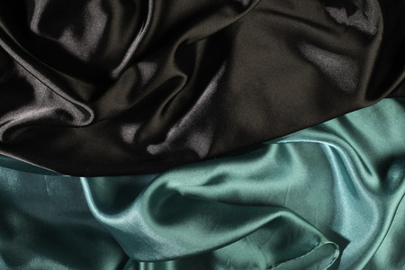 Shiny black and green satin pleated fabric background. Close upの写真素材