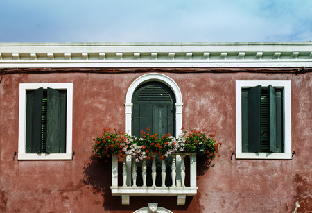 Green venetian windows with flowers. Red wallの写真素材