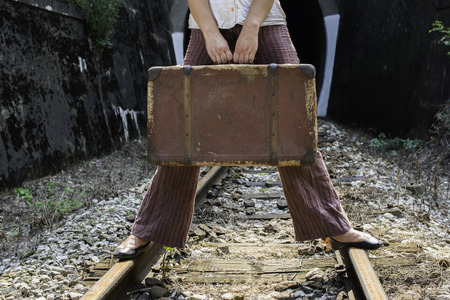 Woman and vintage suitcase on railway road and tunnel. の写真素材