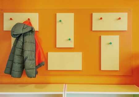 Green jacket hanging on a children's hangerの素材