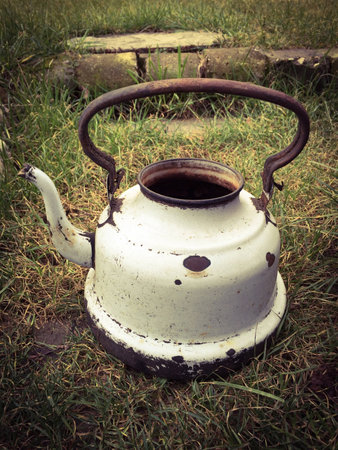 Old white battered kettle on meadowの素材