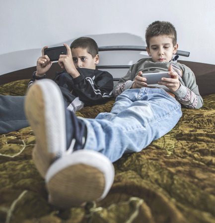 Children playing with their smartphones. Two boys with mobile phones