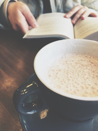 Girl reading a book in a cafe. Cup of coffee and bookの素材