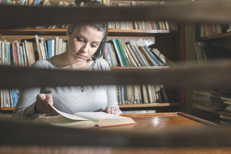 Student girl in a library. Looking at bookの写真素材