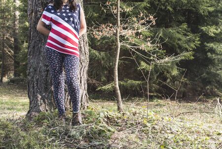 Pregnant woman in the forest. American national flag shirt