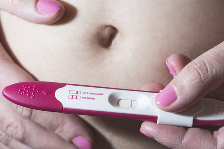 Pregnant woman holding a pregnancy test. Close upの写真素材
