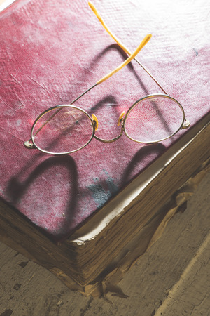 Old vintage round glasses and old book. Low lightの写真素材