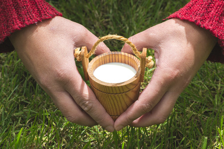 Women hold small wooden mug of milkの写真素材