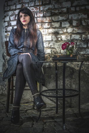 Woman sitting on a chair in coffee shop. Vintage brick wall backgroundの写真素材
