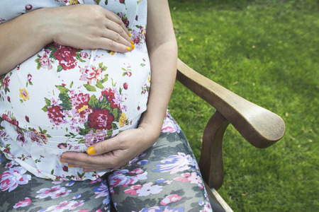 Pregnant women hold picture of womb. Daylight in the gardenの写真素材