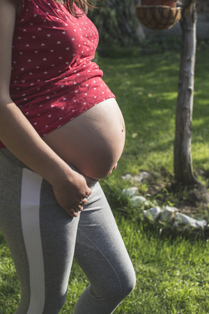 Pregnant woman shows his belly. In the nature. Green meadowの写真素材