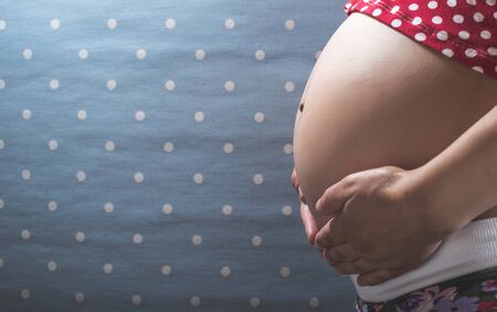 Pregnant woman shows his belly. Blue backgroundの写真素材