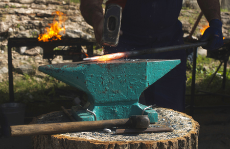 Blacksmith forges iron on anvil. Heated red ironの写真素材