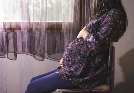 Pregnant women to the window. Violet colorsの写真素材