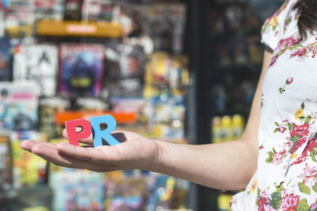 Women hold wooden letters PR. Magazines and newspapers on the backgroundの写真素材