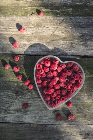 Raspberries in a bowl on wood. Heart shape bowl.の写真素材