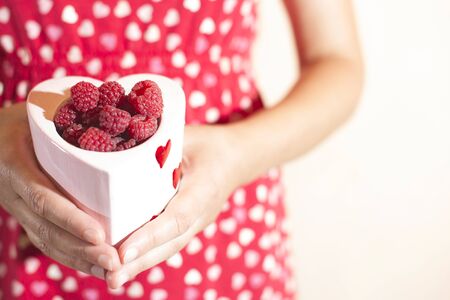 Woman in red dress holding a cup of raspberries
