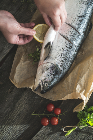 Preparing whole salmon fish for cooking. Vegetables on the table. Vintage styleの写真素材