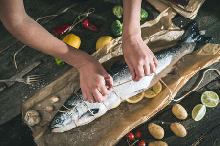 Tying a rope on fish for grilling. Baking paperの写真素材