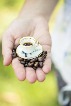 Hand hold very small cup of coffee. Miniature cupの写真素材