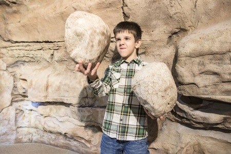 Strong child holds heavy stones.の写真素材