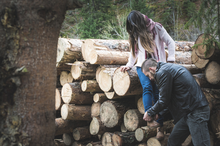 Young woman and men on wood logs in the forestの写真素材