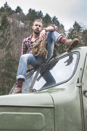Young man on vintage truck with logs in the forest.の写真素材