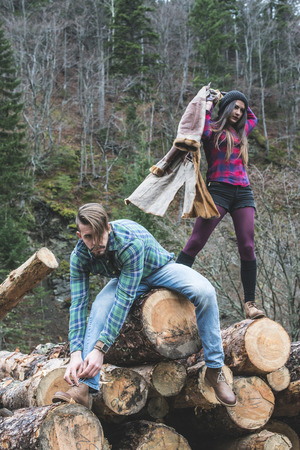 Young woman and men on wood logs in the forestの写真素材