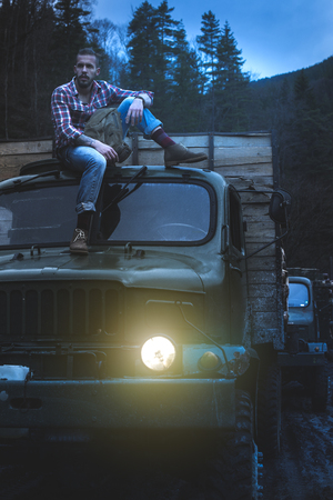 Young man on vintage truck with logs in the forest.の写真素材