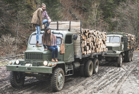 Young man and girl on truck with logs in the forestの写真素材