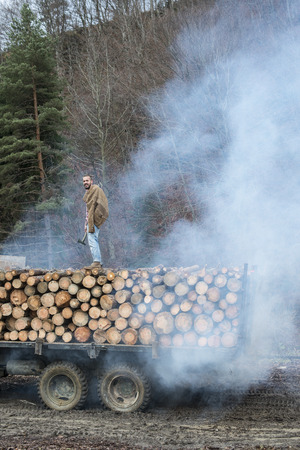 Young man on vintage truck with logs in the forest.の写真素材