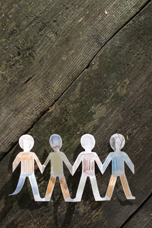 Paper made people figures. Painted white figures on wooden boardの写真素材