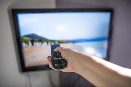 TV and remote control. Hand hold remote.