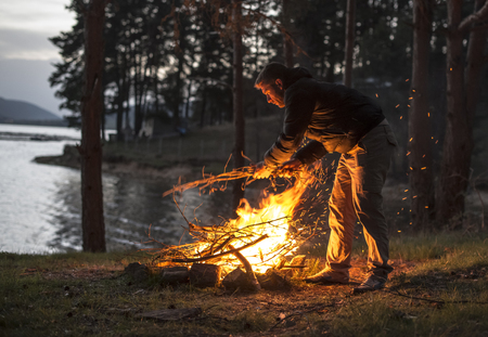 Man lights a fire in the fireplace in nature at night.の写真素材