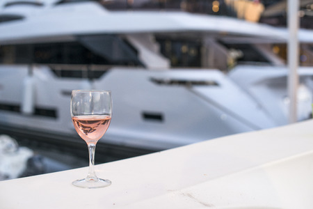 Glass of rose wine and a yacht on the backgroundの写真素材