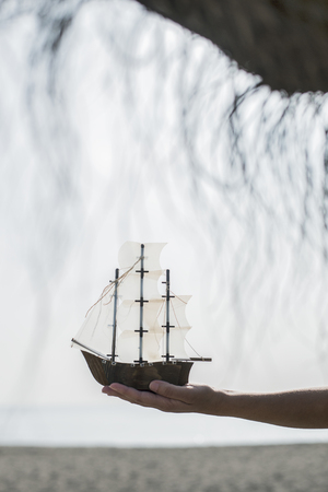 Woman with hat hold boat model on the beachの写真素材