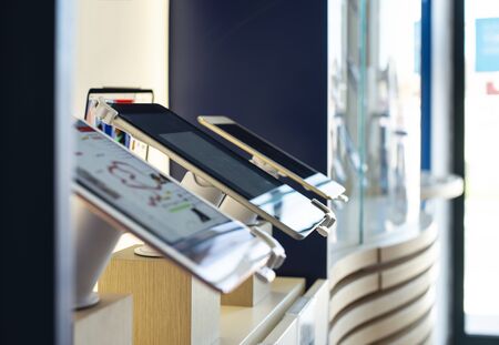 Cell Phones on shelf in telecommunication shop. Lights over GSM phones. Showcase in store for...