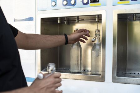 Mineral Water machine on the street. Filling mineral water bottles from a water dispenser. Pay and...