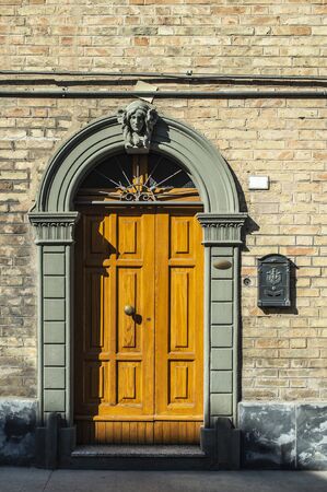 Old typical italian wooden door. Italian house. Ancient house facade. Sunlight. Round door arch. Stone build house. Wrought iron door handles.の写真素材