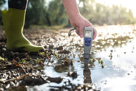 Measure water content with digital device. Sunrise over the water. PH meter.の写真素材