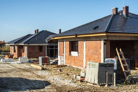 Building a new brick house with black roof. Small houses on construction site. Conception for new home, real estate and constructions.の写真素材