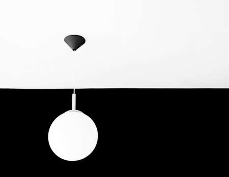 White lamp on white ceiling facing black wallの写真素材