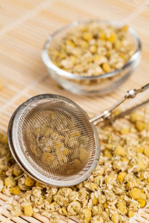 Dry chamomile with tea strainer and glass dish in preparation of the chamomile teaの写真素材