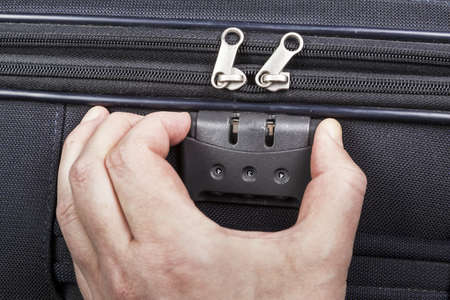Man opens numbered lock on the suitcase zipper during packing for the trip