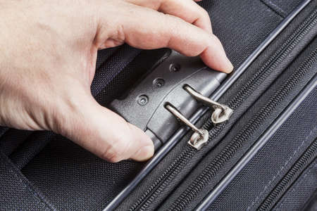 Man opens numbered lock on the suitcase zipper during packing for the tripの写真素材
