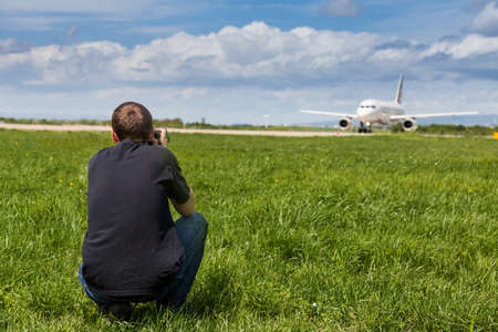 Airplane spotter taking pictures of an airplane which is ready to take off from the runwayの写真素材