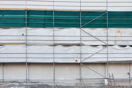 Reconstruction site, wall in scaffolding with green protective cloth